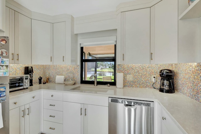 kitchen with stainless steel dishwasher, decorative backsplash, white cabinets, and sink