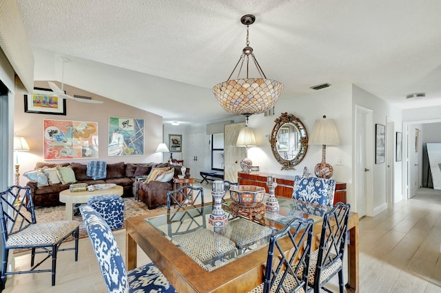 dining room with light wood-type flooring and a textured ceiling