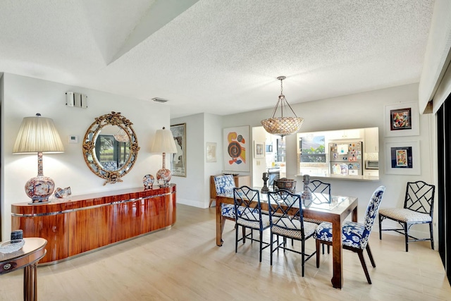 dining area featuring a textured ceiling and light hardwood / wood-style flooring