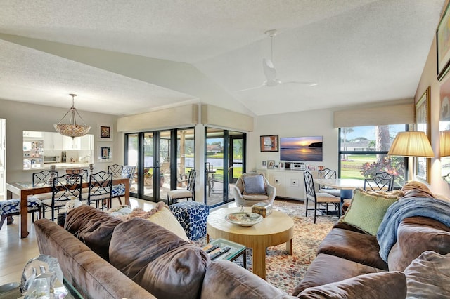 living room featuring ceiling fan, french doors, a textured ceiling, vaulted ceiling, and light wood-type flooring