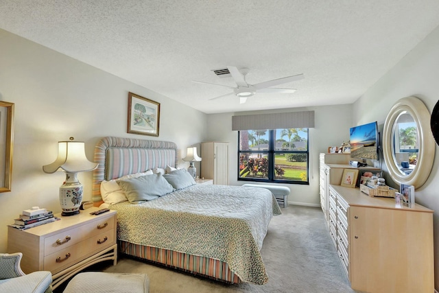 bedroom with ceiling fan, light carpet, and a textured ceiling