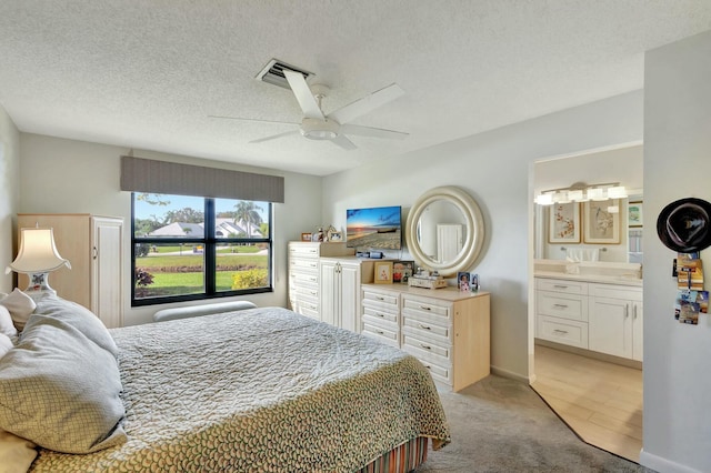 carpeted bedroom with a textured ceiling, ceiling fan, and ensuite bathroom