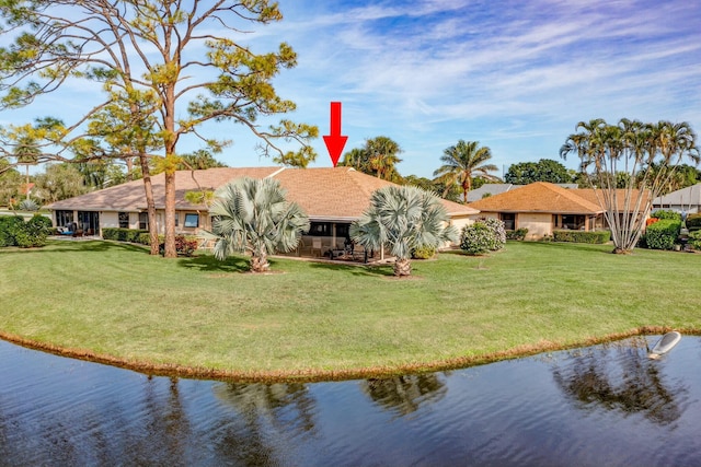 back of property with a lawn and a water view