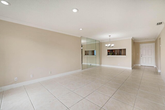 spare room with ornamental molding, light tile patterned floors, a notable chandelier, and a textured ceiling