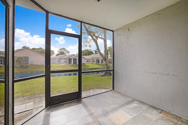 unfurnished sunroom featuring a water view