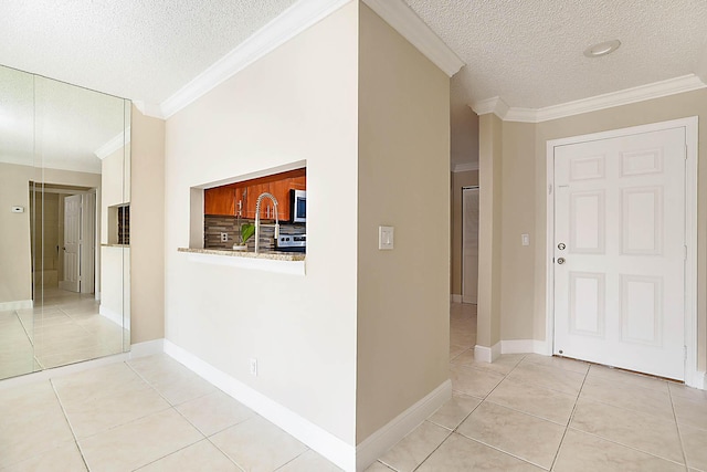 hallway with ornamental molding, a textured ceiling, and light tile patterned floors