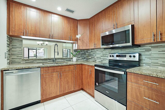 kitchen featuring light stone countertops, appliances with stainless steel finishes, sink, and decorative backsplash