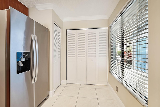 kitchen with light tile patterned floors, stainless steel fridge, ornamental molding, and a textured ceiling