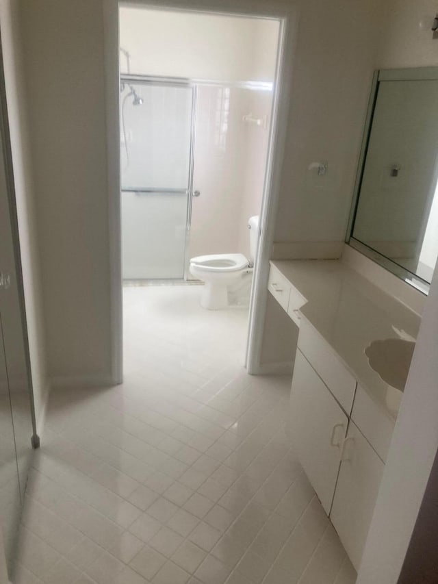 bathroom with toilet, vanity, tile patterned floors, and a shower with door