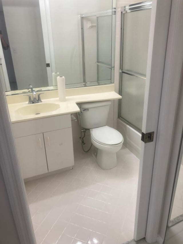 full bathroom featuring tile patterned floors, vanity, enclosed tub / shower combo, and toilet