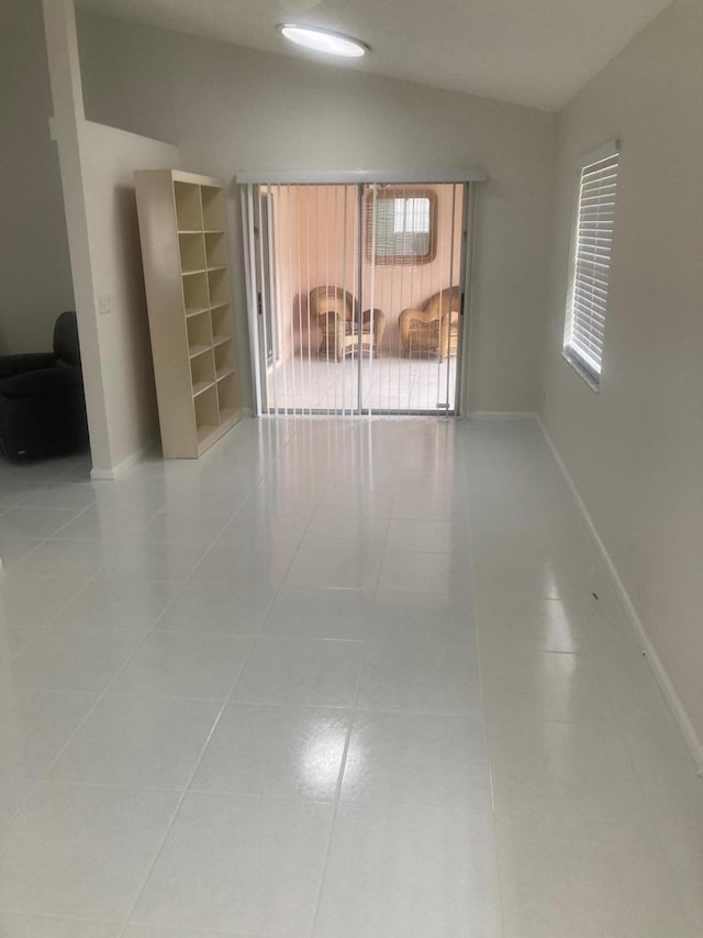 tiled spare room featuring vaulted ceiling