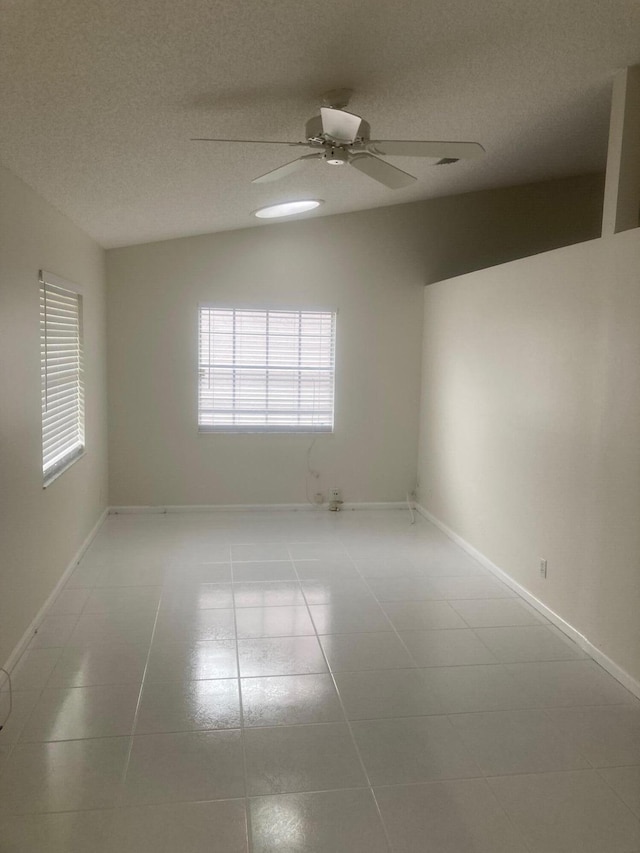 empty room featuring light tile patterned floors, a textured ceiling, vaulted ceiling, and ceiling fan