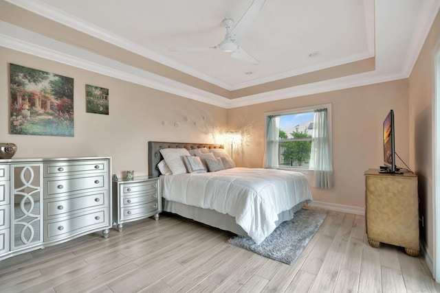 bedroom featuring ceiling fan, ornamental molding, a tray ceiling, and light hardwood / wood-style flooring