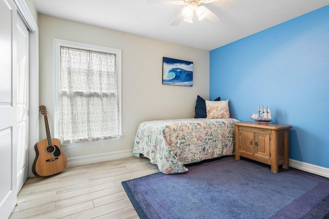 bedroom with ceiling fan, a closet, light hardwood / wood-style floors, and a textured ceiling