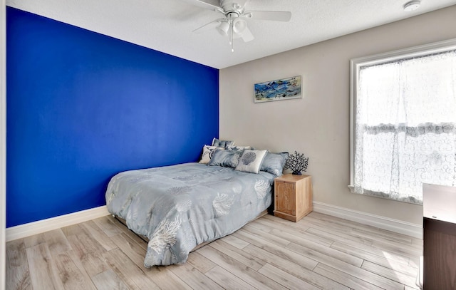 bedroom featuring ceiling fan, a textured ceiling, and light wood-type flooring