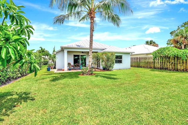 back of property featuring ceiling fan and a yard