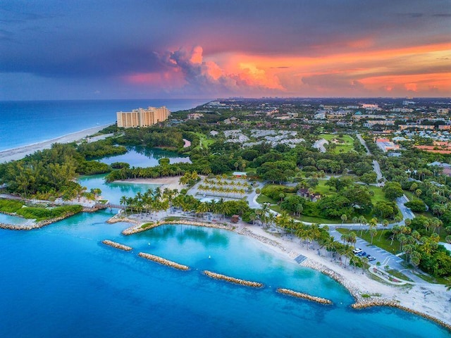 aerial view at dusk with a water view and a beach view