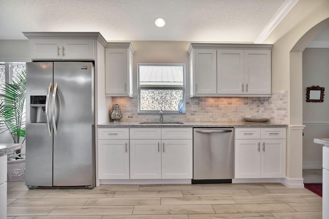 kitchen with light stone countertops, sink, white cabinets, and appliances with stainless steel finishes