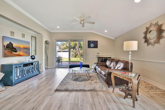 living room featuring ceiling fan, light hardwood / wood-style floors, ornamental molding, and vaulted ceiling