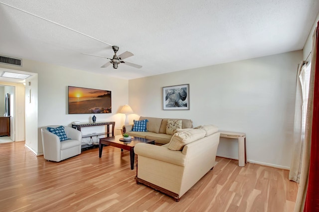 living room with a textured ceiling, ceiling fan, and wood-type flooring