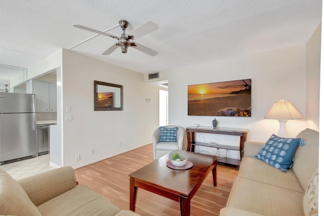 living room featuring a textured ceiling, ceiling fan, and light wood-type flooring