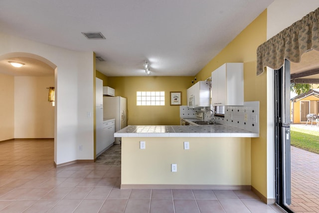 kitchen featuring white cabinetry, sink, tile counters, kitchen peninsula, and white appliances