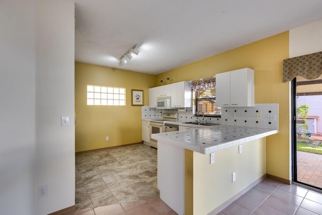 kitchen with tile countertops, sink, white cabinets, kitchen peninsula, and white appliances