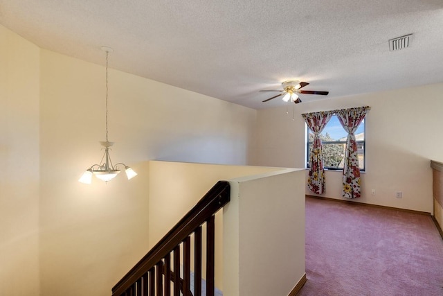 corridor featuring carpet flooring, a textured ceiling, and a chandelier