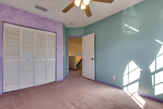 unfurnished bedroom featuring ceiling fan, light colored carpet, and a closet