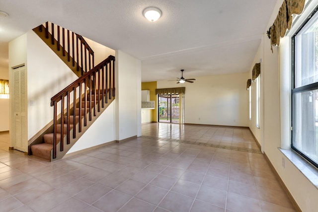 interior space featuring ceiling fan, a textured ceiling, and light tile patterned floors