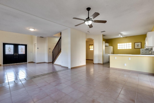 unfurnished living room featuring ceiling fan, sink, a textured ceiling, and light tile patterned floors