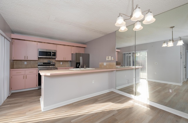 kitchen featuring pendant lighting, backsplash, appliances with stainless steel finishes, and an inviting chandelier