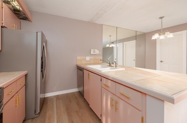 kitchen with kitchen peninsula, sink, hanging light fixtures, and appliances with stainless steel finishes