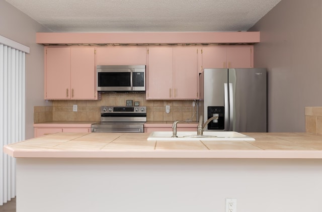 kitchen with cream cabinets, a textured ceiling, stainless steel appliances, and sink