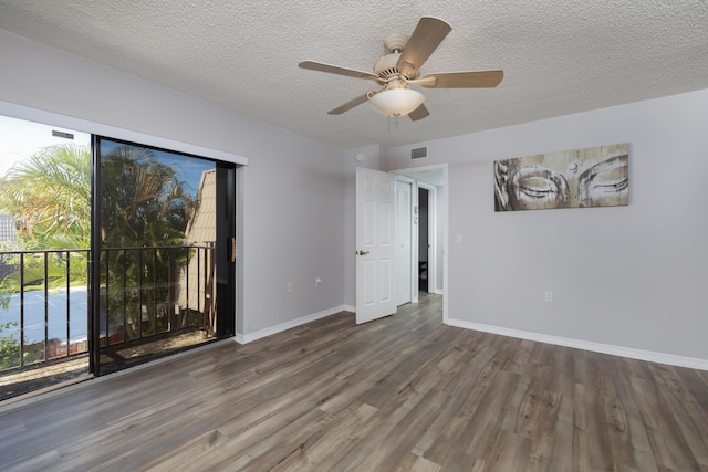 spare room with a textured ceiling, ceiling fan, and dark wood-type flooring