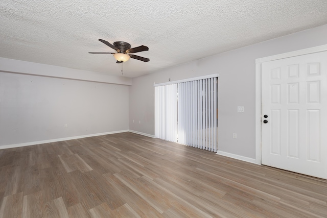 empty room with ceiling fan, light wood-type flooring, and a textured ceiling