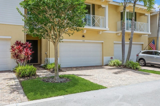 townhome / multi-family property with stucco siding, a garage, and decorative driveway