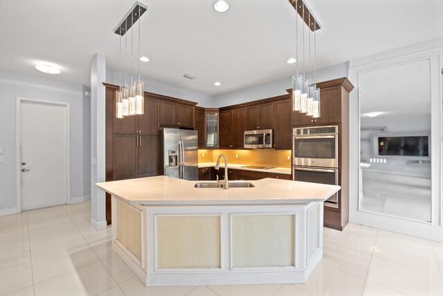 kitchen featuring dishwasher, a kitchen island with sink, sink, hanging light fixtures, and light tile patterned floors