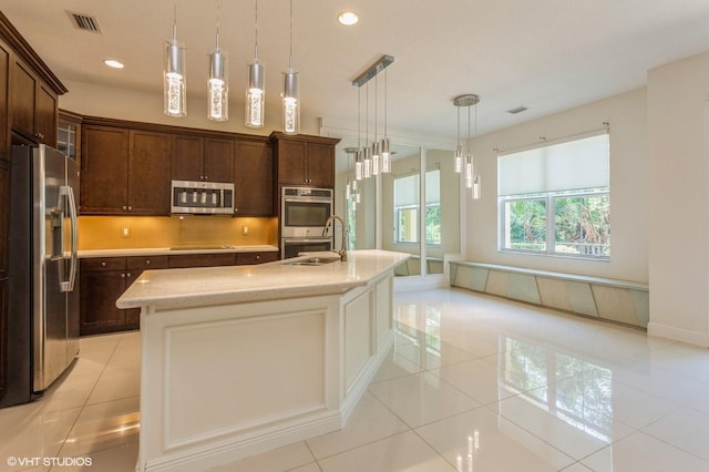 kitchen with stainless steel appliances, light tile patterned floors, a sink, recessed lighting, and a kitchen island with sink