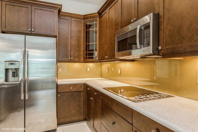 kitchen featuring appliances with stainless steel finishes, glass insert cabinets, and dark brown cabinetry