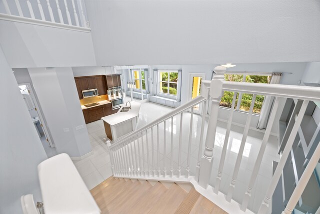 stairs with wood-type flooring and a towering ceiling