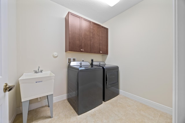 clothes washing area featuring cabinets, a textured ceiling, and washer and clothes dryer