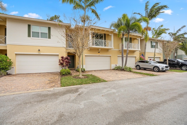 view of property featuring stucco siding, decorative driveway, and a garage