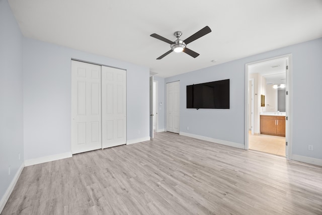 unfurnished bedroom featuring ensuite bath, ceiling fan, light hardwood / wood-style floors, and two closets