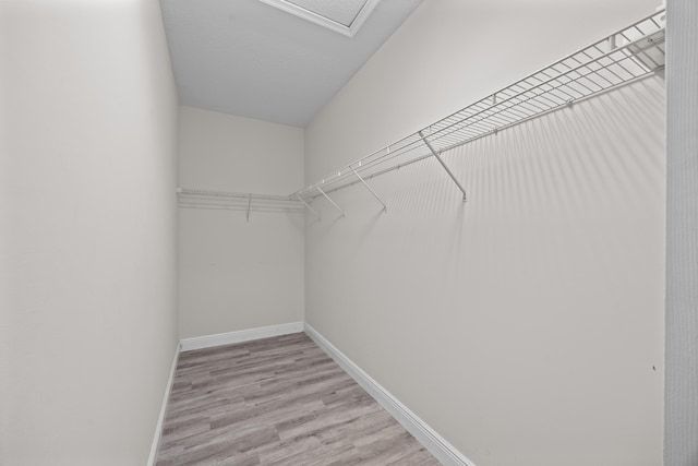 spacious closet with wood finished floors and attic access