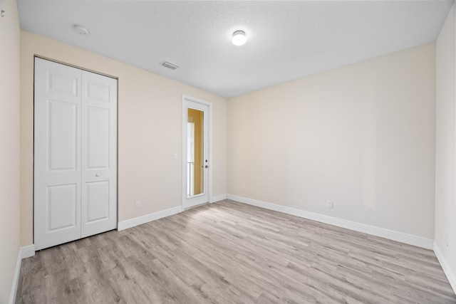 unfurnished bedroom with light wood-style flooring, baseboards, and a closet