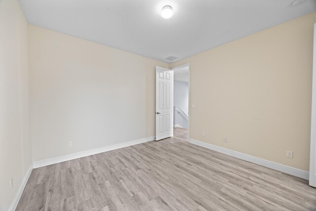 unfurnished bedroom featuring a textured ceiling, light wood-type flooring, and a closet