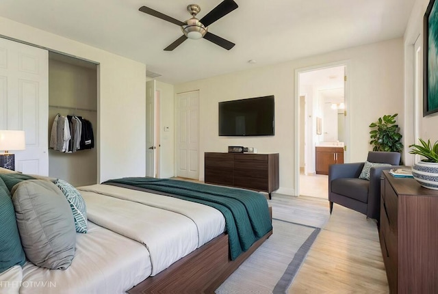 bedroom with a closet, light wood-type flooring, ensuite bath, a ceiling fan, and baseboards