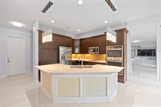 kitchen with sink, stainless steel appliances, decorative light fixtures, a center island with sink, and light tile patterned flooring