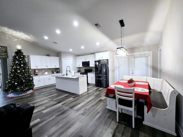 kitchen featuring black appliances, white cabinets, hanging light fixtures, an island with sink, and tasteful backsplash